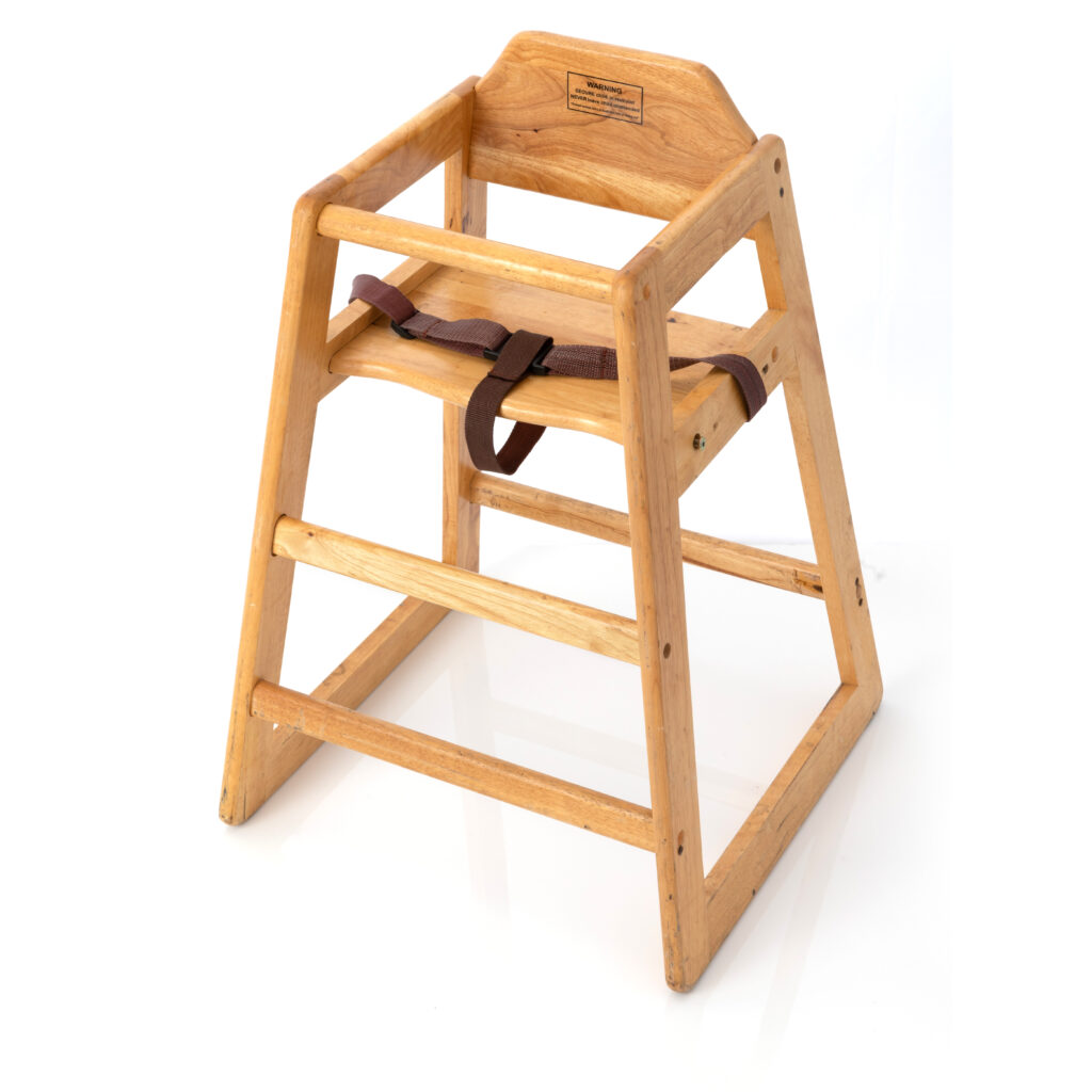This high chair, available for rent in Forsyth County, features a natural wooden finish, angled legs, and a safety strap. Designed with open sides and a backrest, it is perfect for young children and beautifully photographed against a white background.