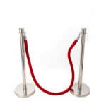 In the heart of Atlanta, T3 Event Rentals offers elegant crowd control solutions with two silver stanchions connected by a luxurious red velvet rope, set against a simple white backdrop. Perfect for any event needing effective area division. Rent yours today!.
