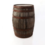 A whiskey barrel with metal bands stands on a white background, highlighting its rustic charm for events in Atlanta. Its visible grain texture and aged features narrate tales of mellowed spirits. This item is available for rent only through T3 Event Rentals.