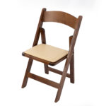 T3 Event Rentals proudly presents the Fruitwood Folding Chair, part of a set of 5, displayed unfolded against a white backdrop. The chair features a light beige cushioned seat that highlights its simple and functional design. Perfect for events in Atlanta, this rental option elevates any occasion with ease and style.