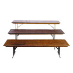 Three Rectangle Folding Tables, showcasing straightforward designs and metal legs with signs of wear on the surfaces, are arrayed in descending size order from back to front against a plain white background. This setup is perfect for events in Atlanta. Enhance your next event with table rentals from T3 Event Rentals, your trusted partner located in Alpharetta but serving all of North Georgia. Remember, all items are available for rent only; nothing is for sale.