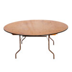 A minimalist, round wooden table from T3 Event Rentals, featuring a smooth surface and metal folding legs, stands out against a plain white background. Perfect for events in Dahlonega.