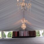 A photo of the reception area of a wedding displaying tent liners draped down from the top.