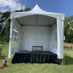 10x10 high peak tent with windowed sidewalls, a stage, and skirting.