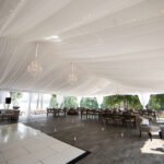 A photo of the reception area of a wedding displaying tent liners draped down from the top.