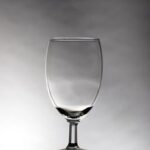 The Amber Vintage Glass from T3 Event Rentals is elegantly displayed in the heart of Dahlonega, set on a reflective dark surface that highlights its beauty against a gradient gray background. Expert lighting brings out subtle reflections and shadows with hints of amber, perfect for enhancing your events decor. Choose T3 Event Rentals for all your rental needs in Dahlonega and beyond.