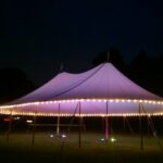 Sailcloth tent at night with perimeter lighting and LED uplights