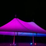 Sailcloth tent at night with perimeter lighting and LED uplights