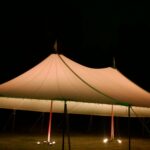 Sailcloth tent at night with perimeter lighting and LED uplights
