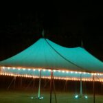 Sailcloth tent at night with perimeter lighting and LED uplights