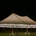 Sailcloth tent at night with perimeter lighting and LED uplights