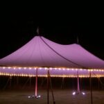 Sailcloth tent at night with perimeter lighting and LED uplights