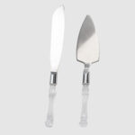 Discover our Cake Server - 2 Piece Set from T3 Event Rentals, perfect for your events in Atlanta. This set features decorative clear handles and includes a straight-blade knife and a triangular server with shiny silver ends, beautifully capturing the light on a plain background. Ideal for any event need, our rentals provide the elegance youre looking for without purchasing.