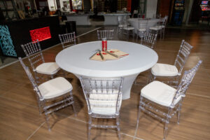A circle table with ghost chiavari chairs with white cushions