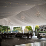 T3 Event Rentals brings elegant sofas, tables, and chandeliers to Dahlonega venues with white draped ceilings and greenery views.