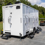 Four stall restroom trailer with climate control, steps and levelling jacks set on a paved drive