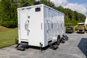Four stall restroom trailer with climate control, steps and levelling jacks set on a paved drive