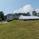 Aerial view of a 50x100 white top frame tent set on a lawn with ceremony seating