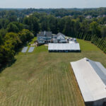 High aerial showing a 50x100 frame tent in place on a large open lawn
