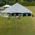 Gable end of a white top frame tent with tables set beneath
