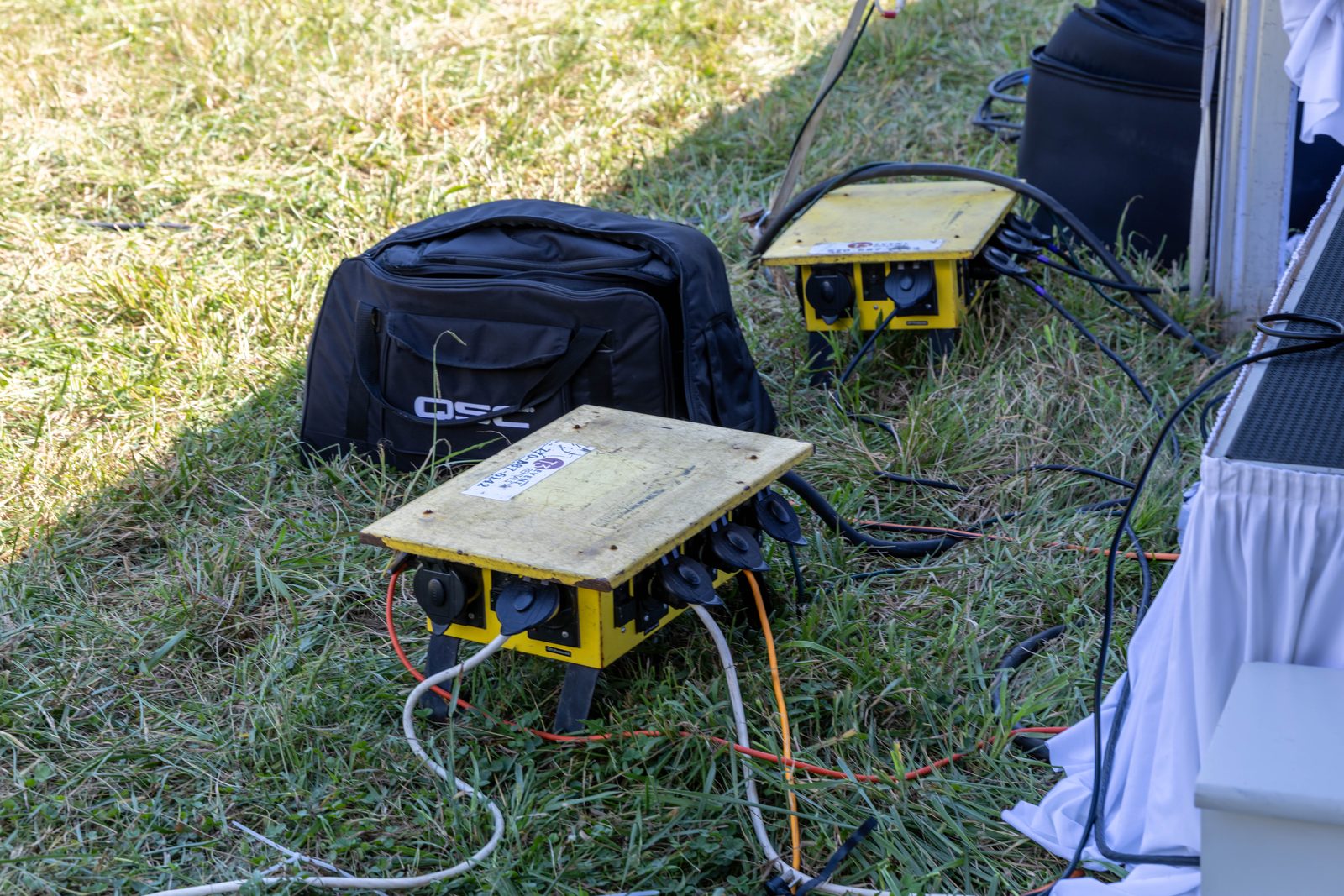 Power distribution boxes and cables on the grass near the stage.