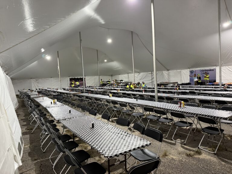 Lit dining tent with long rows of tables and chairs for utility crews
