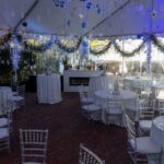 Wide view inside the tent with tables set and sidewalls closed around the room.