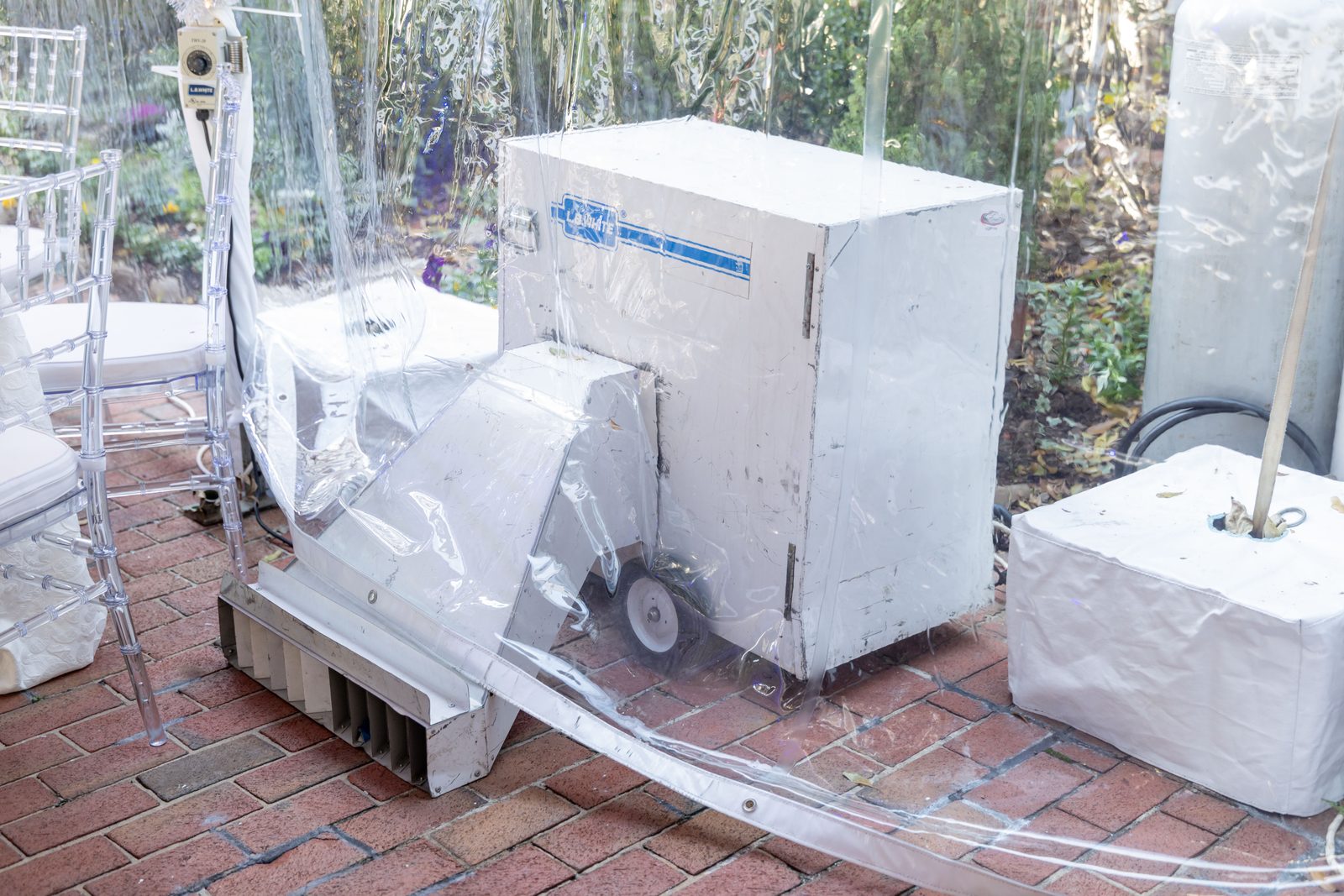 A second tent heater outside the tent, with a flexible duct running toward the wall.